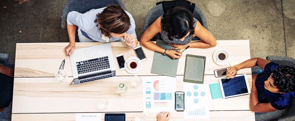 Three Pharma regulatory consultants working at a table and planning their pharma gross-to-net strategy