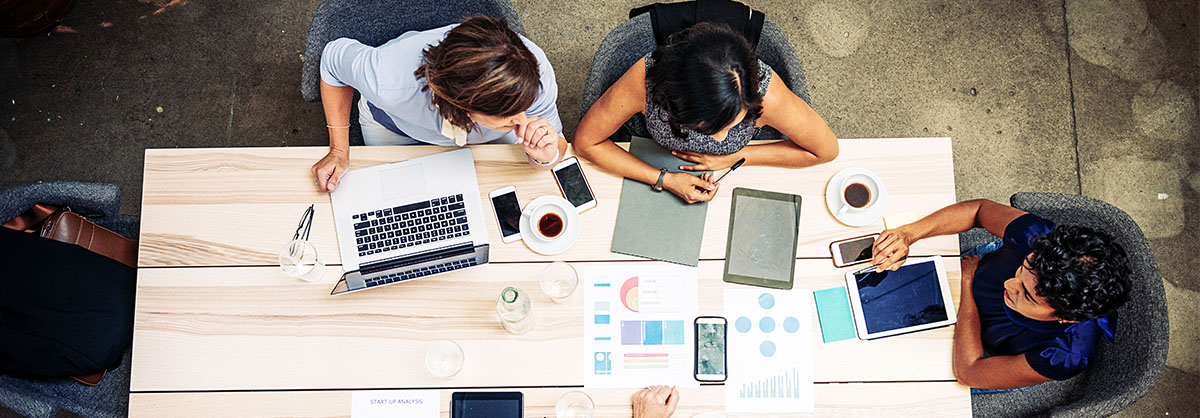 Three Pharma regulatory consultants working at a table and planning their pharma gross-to-net strategy